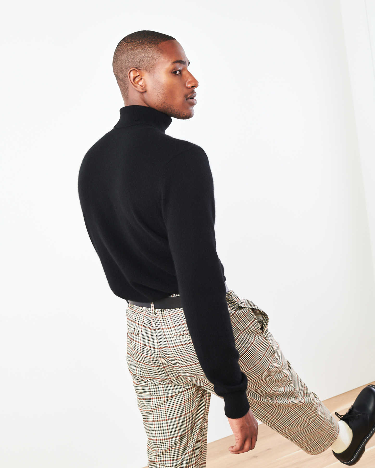 Man wearing men's black cashmere turtleneck sweater strolling