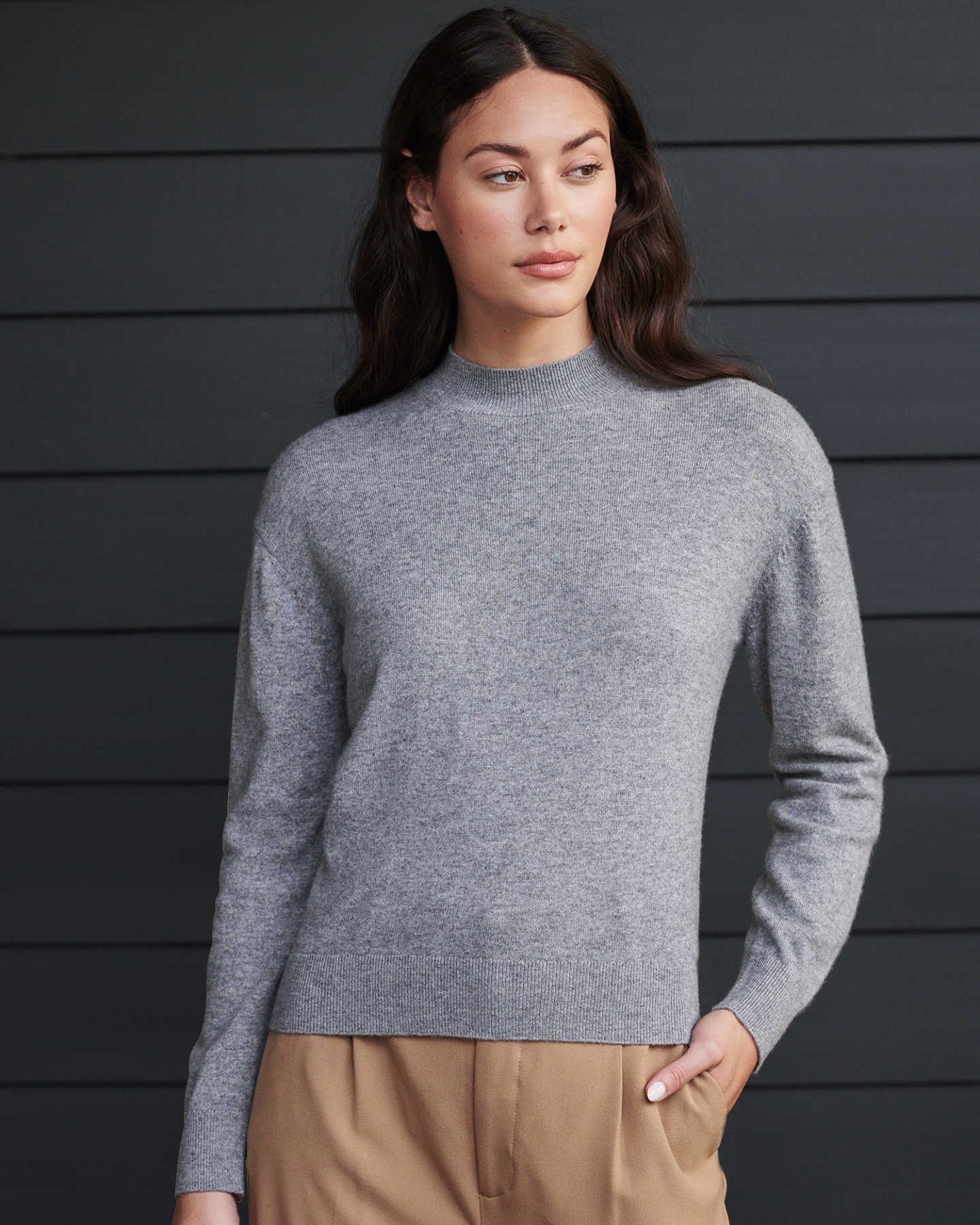 Woman wearing grey cashmere mockneck sweater looking to the side