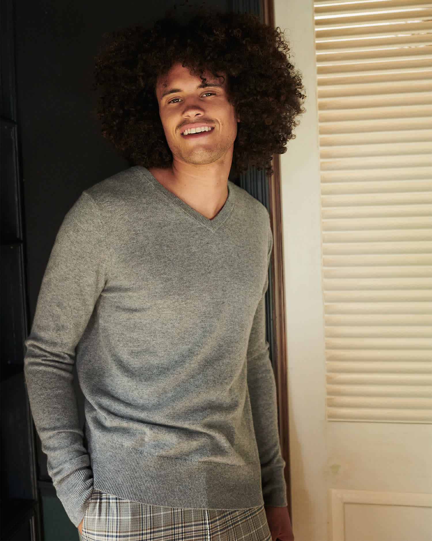 Man wearing grey cashmere v-neck sweater smiling