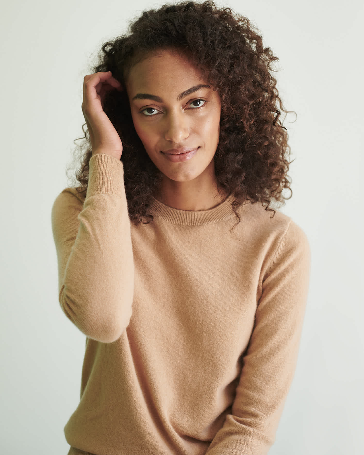 Woman wearing camel cashmere sweater smiling