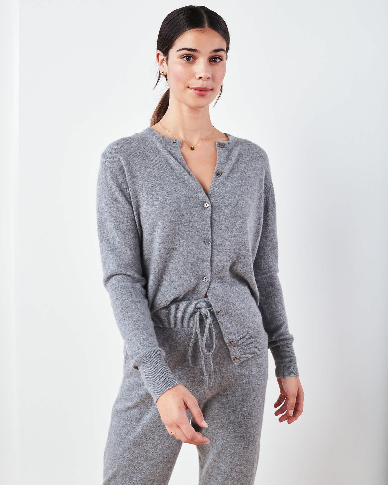 Woman wearing grey cashmere cardigan sweater and grey cashmere sweatpants standing