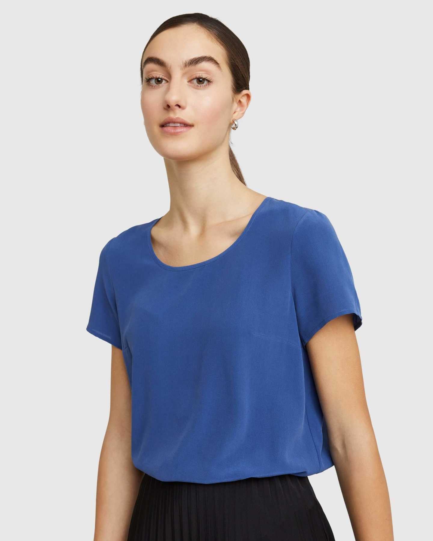 Woman wearing silk tee in blue looking at camera