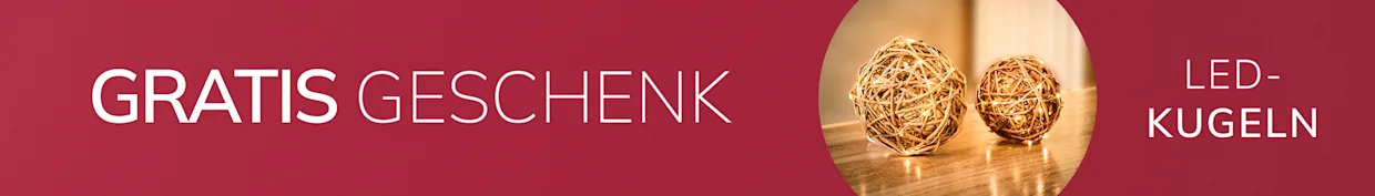 Eine Werbeanzeige mit bordeauxrotem Hintergrund, mit dem Text 'GRATIS GESCHENK*'
Daneben sieht man zwei leuchtende Dekokugeln auf einem Holztisch.
