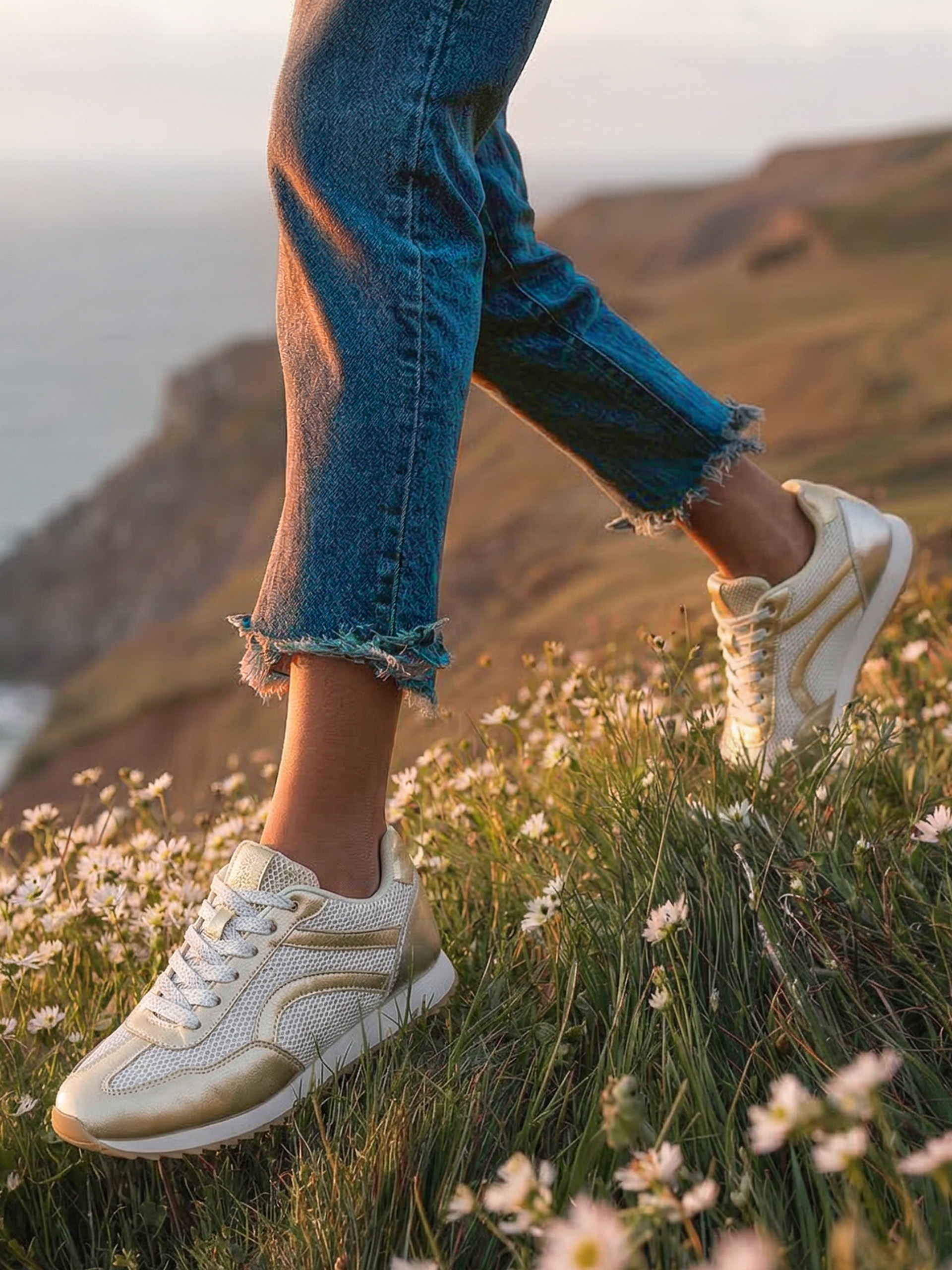 Eine Fußaufnahme von einem Sneaker an der Küste.