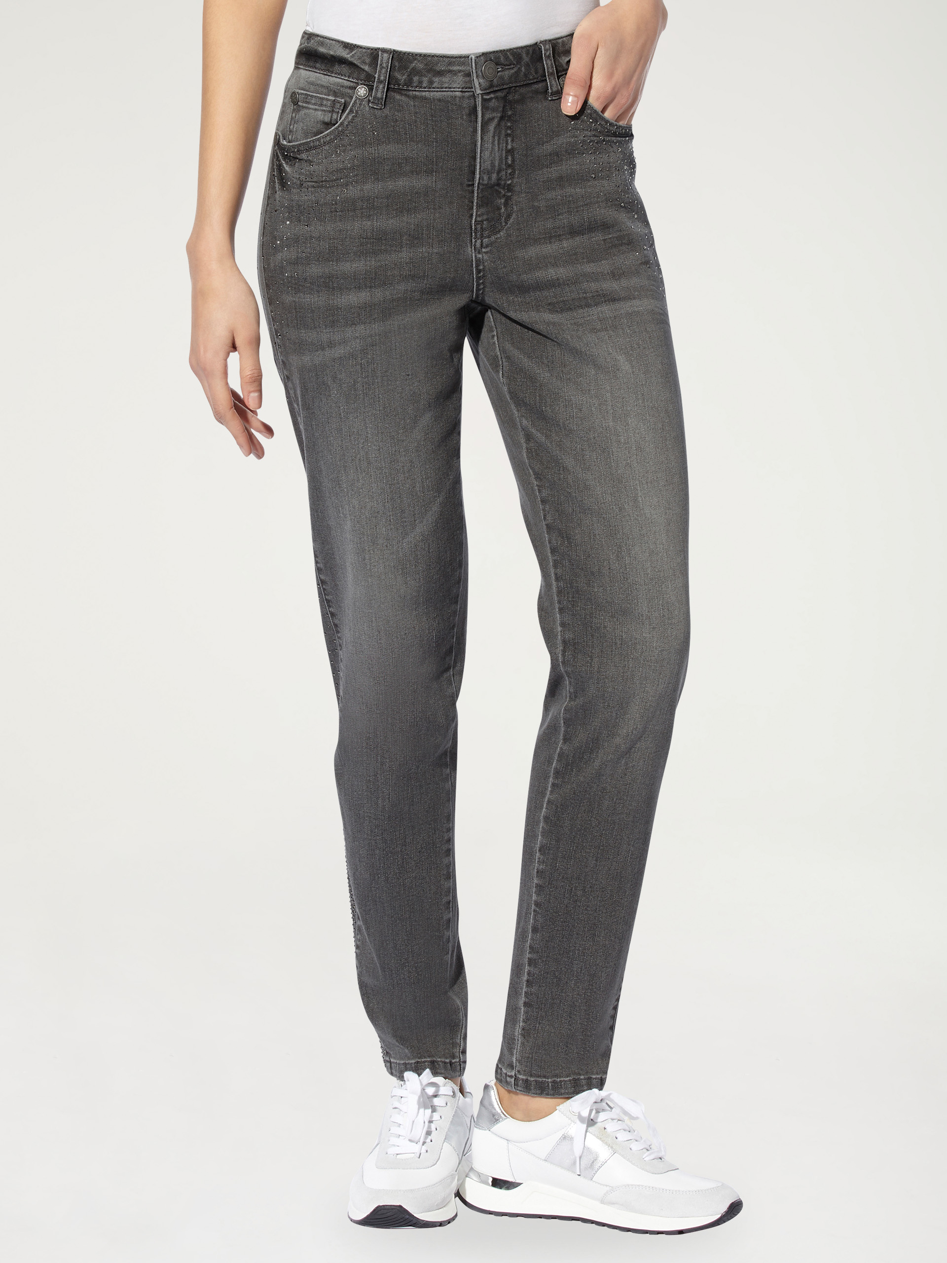Dunkelgraue Damen-Jeans mit geradem Schnitt, kombiniert mit weissen Sneakern und einem weissen Oberteil.