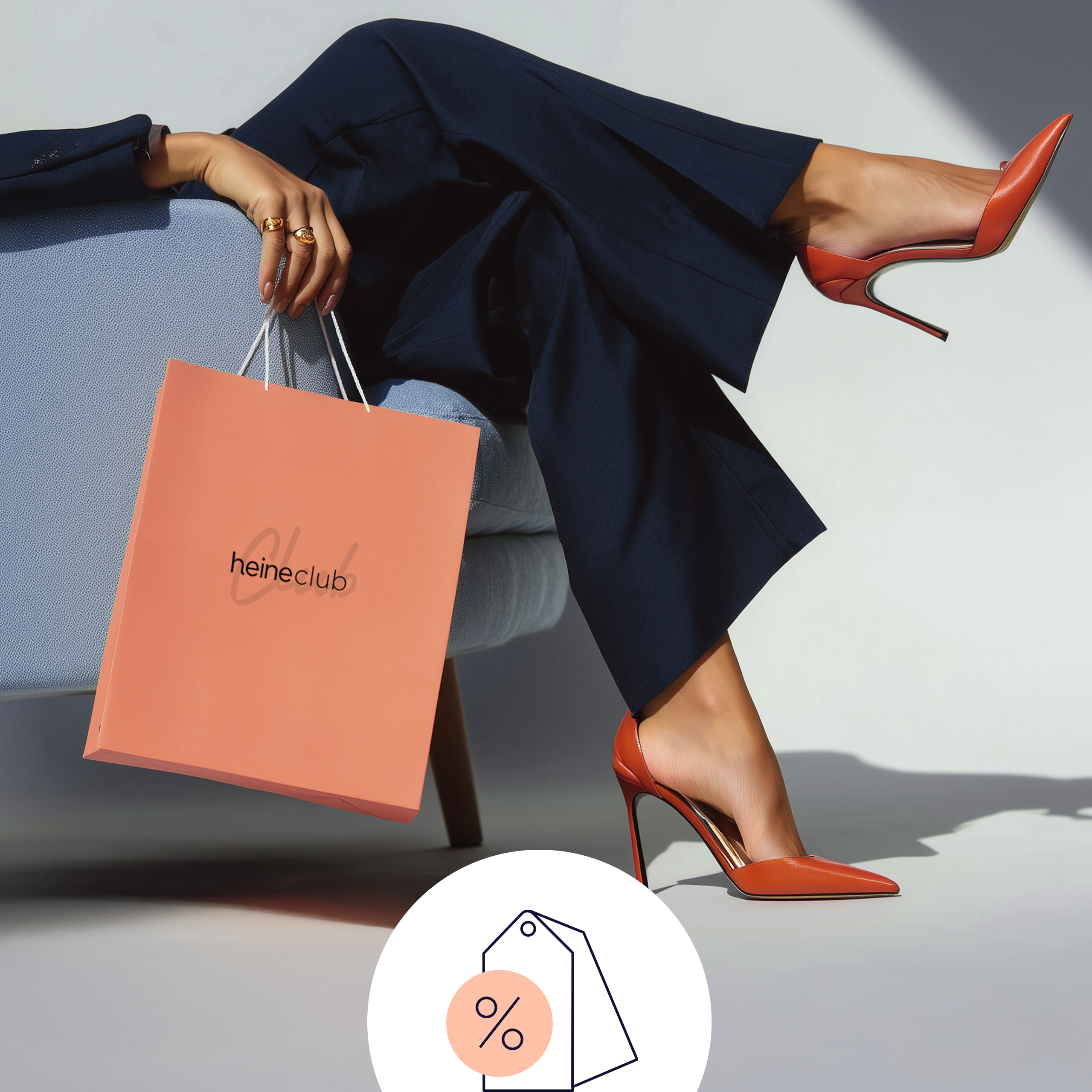 Ein Model sitzt auf einem Stuhl, trägt schwarze Hose und orange High Heels, hält eine orange Einkaufstasche.