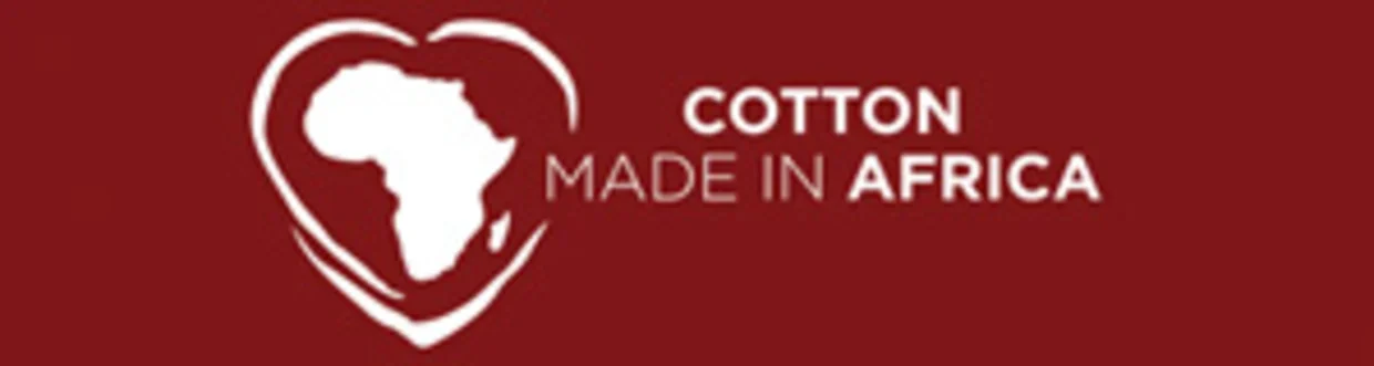 Logo mit weißer Afrika-Kontur in Herzform und Schriftzug `Cotton Made in Africaá auf rotem Hintergrund. Logo mit weißer Afrika-Kontur in Herzform und Schriftzug `Cotton Made in Africaá auf rotem Hintergrund.