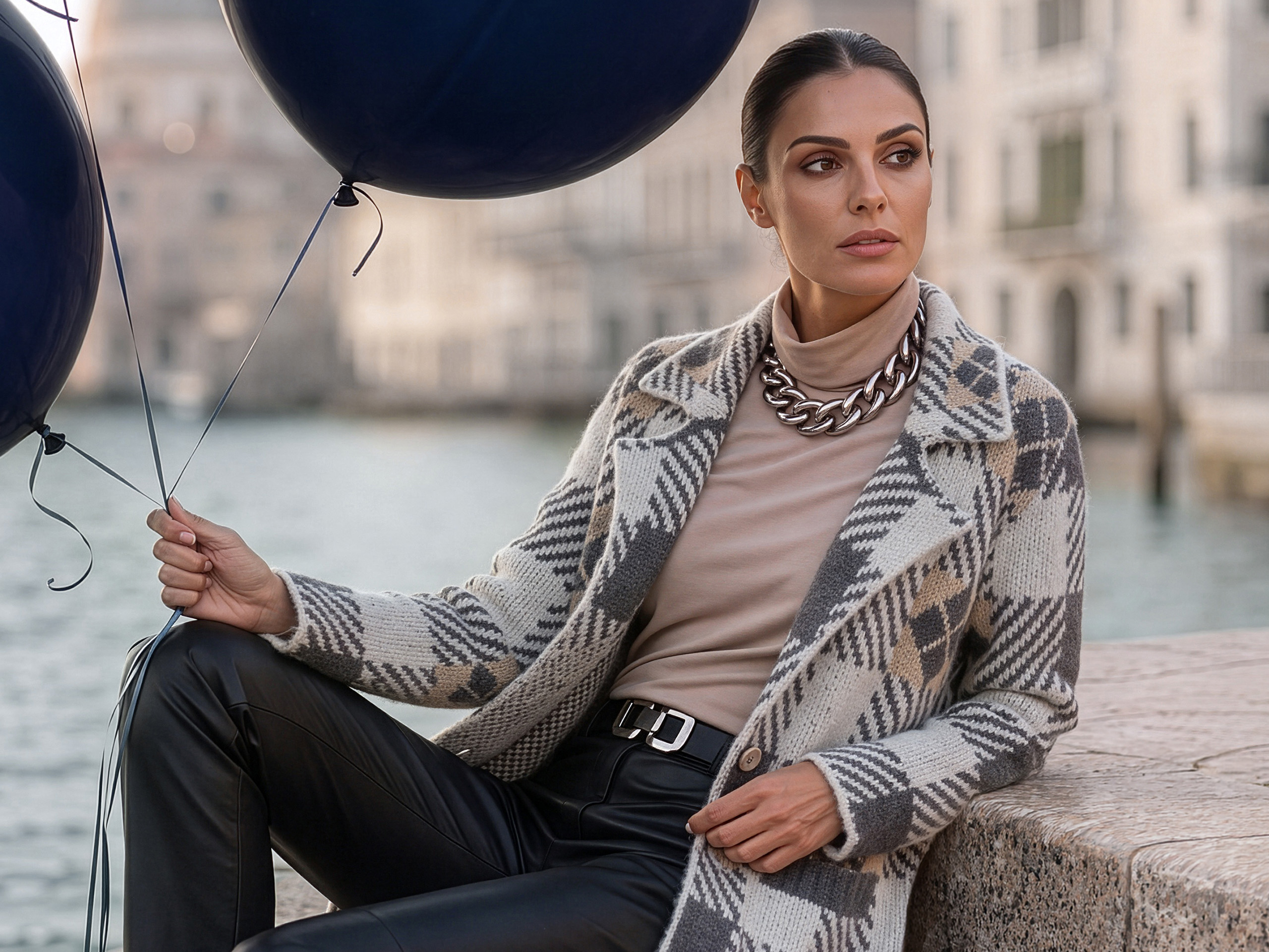 Ein Model am Kanal trägt einen grau gemusterten Cardigan, Rollkragenpullover und schwarze Hose, mit schwarzen Ballons.