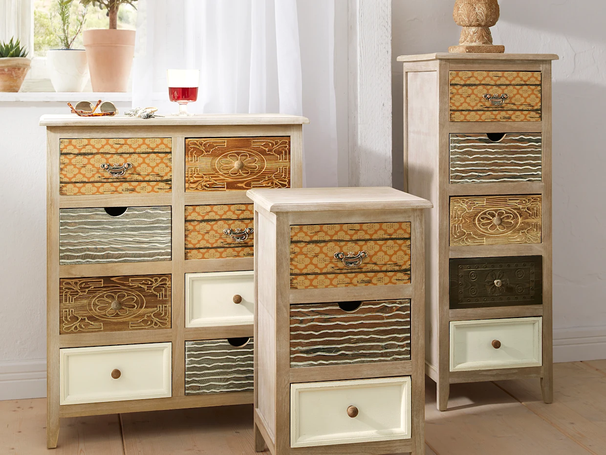 Houten ladekasten met kleurrijke, decoratieve fronten en verschillende patronen, geplaatst in een lichte kamer.