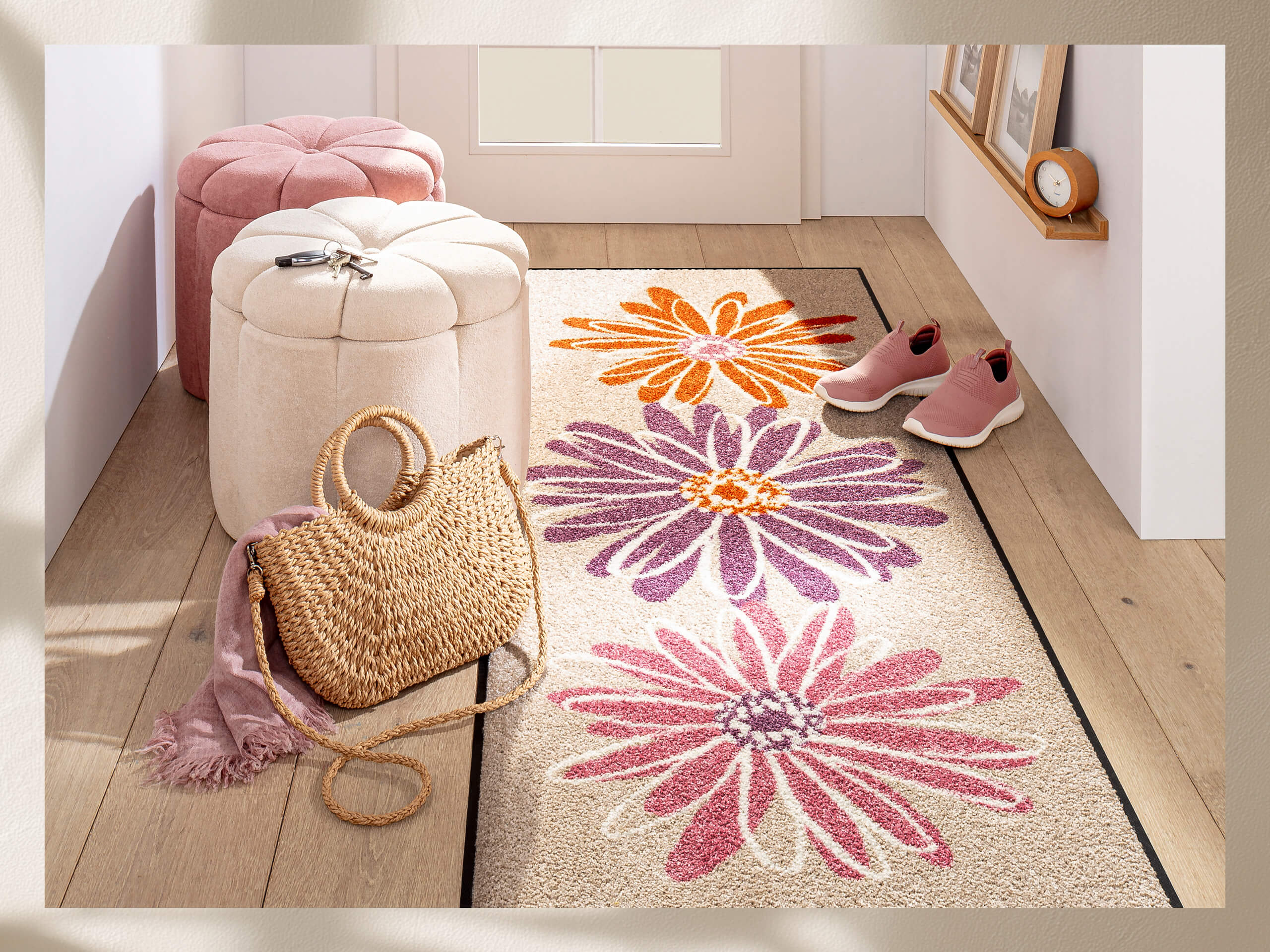Heller Flur mit Läufer, der große Blumen in Orange, Lila und Pink zeigt. Daneben Korbtasche, rosa Schuhe und Sitzhocker.