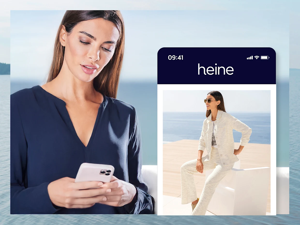 Une femme en chemisier bleu regarde son téléphone portable. À sa droite, un grand téléphone portable avec l'application Heine est simulé. Une femme en chemisier bleu regarde son téléphone portable. À sa droite, un grand téléphone portable avec l'application Heine est simulé.