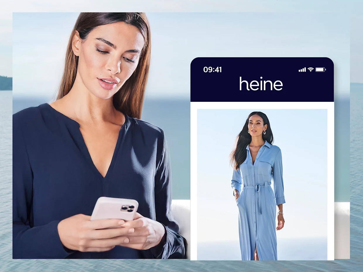Vrouw in blauwe blouse kijkt naar haar mobiele telefoon. Rechts naast haar staat een grote mobiele telefoon met de Heine-app gesimuleerd. Vrouw in blauwe blouse kijkt naar haar mobiele telefoon. Rechts naast haar staat een grote mobiele telefoon met de Heine-app gesimuleerd.