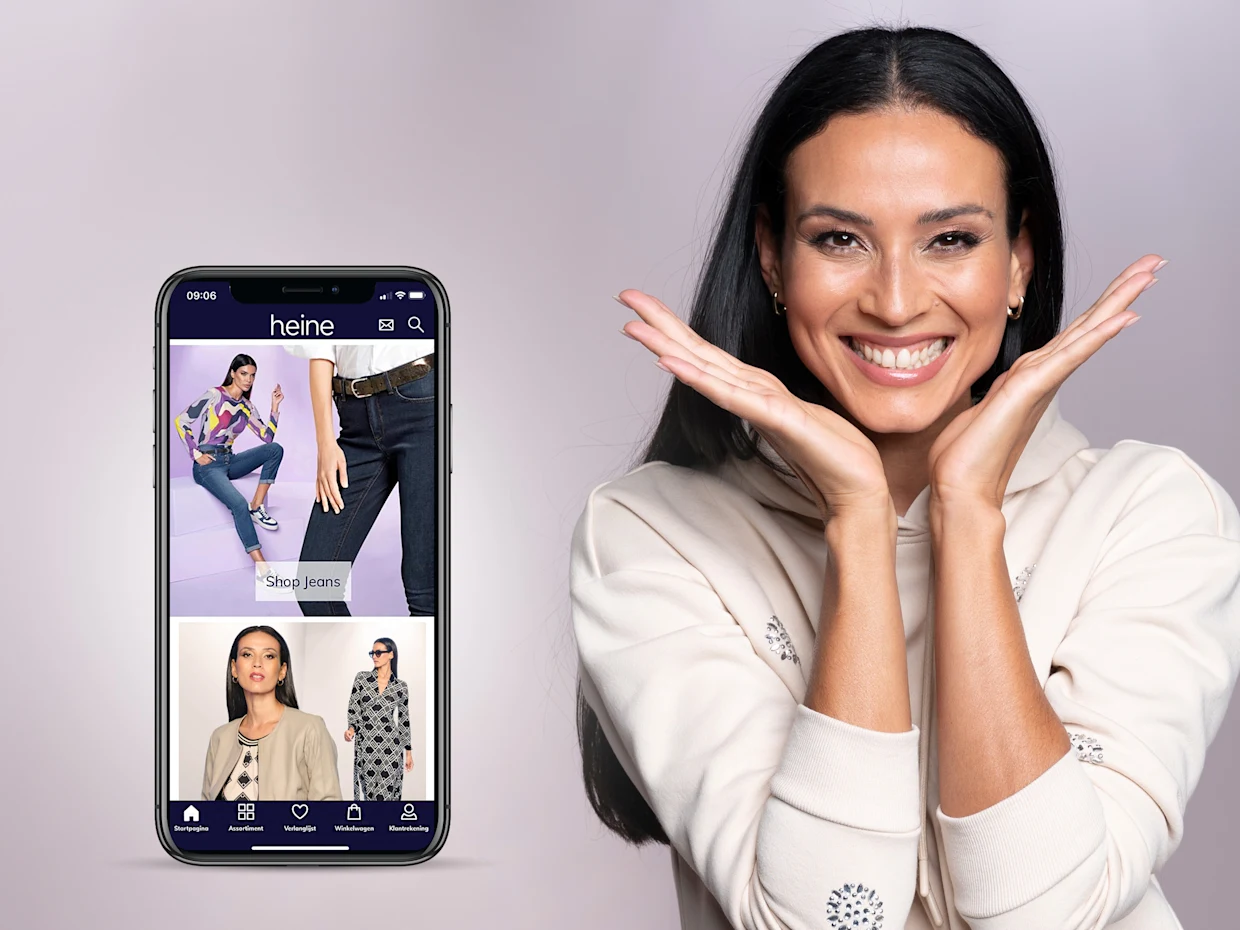 Smartphone met de Heine-shop app geopend, toont modecategorieën zoals jeans en blouses. Smartphone met de Heine-shop app geopend, toont modecategorieën zoals jeans en blouses.