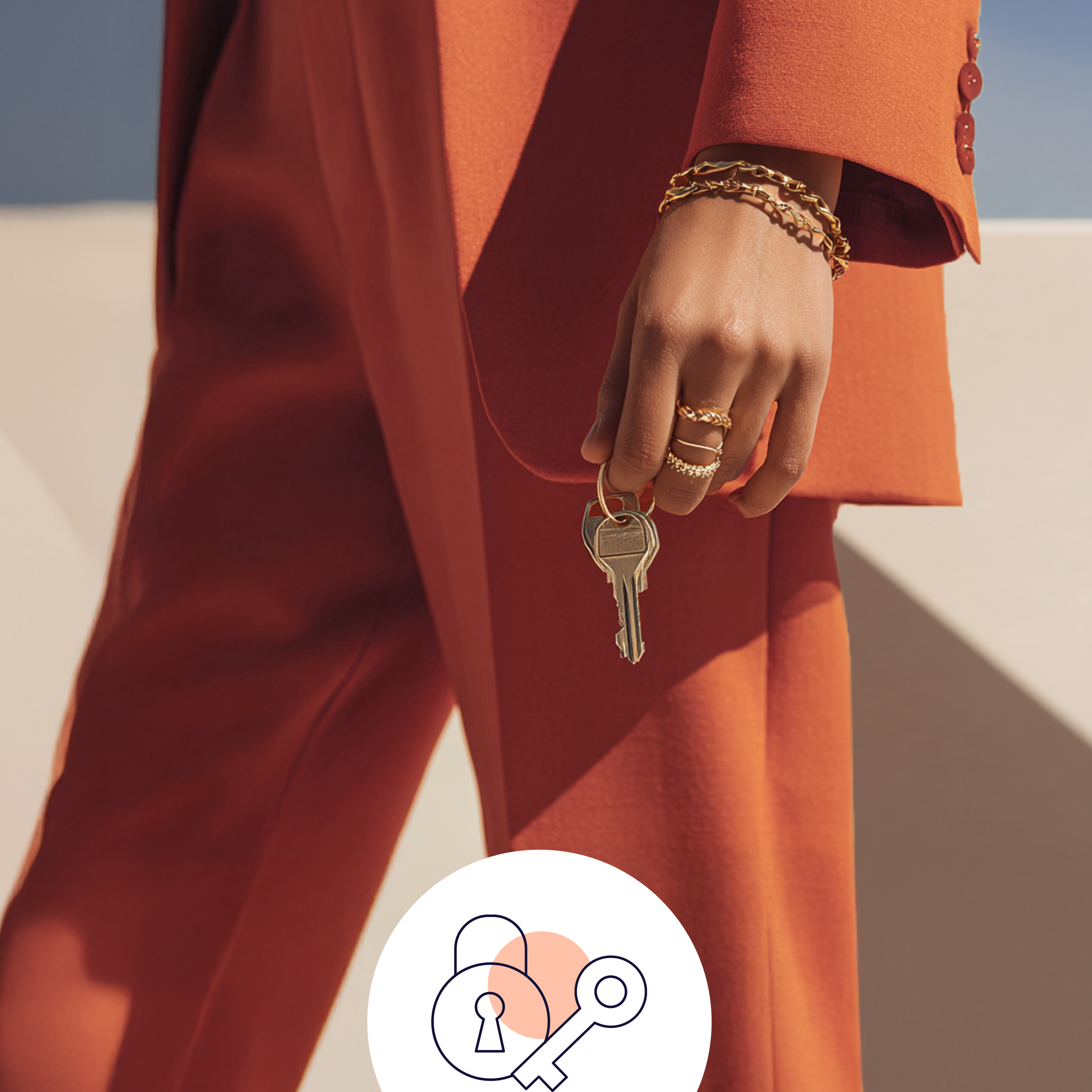 Ein Model trägt einen orangen Anzug und hält einen Schlüsselbund mit zwei Schlüsseln in der Hand.