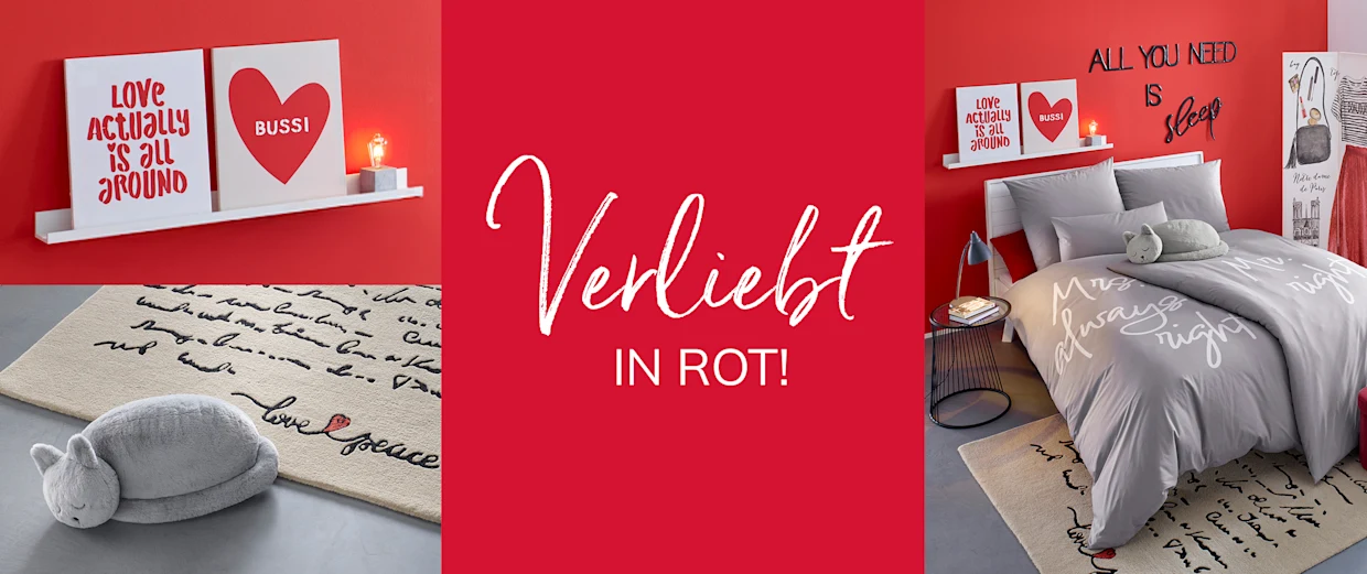Modernes Schlafzimmer mit roter Wand, Dekoschildern, grauer Bettwäsche und Teppich mit Schrift. Im Bild steht der Text 'Verliebt in Rot!'. Modernes Schlafzimmer mit roter Wand, Dekoschildern, grauer Bettwäsche und Teppich mit Schrift. Im Bild steht der Text 'Verliebt in Rot!'.
