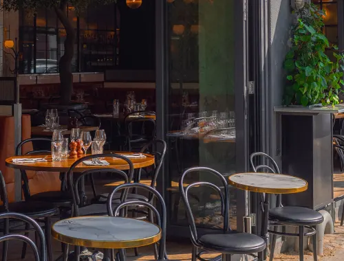 Outdoor seating at a charming café with marble-topped tables and bentwood chairs along with the words 'starting a small business' on top of the image.