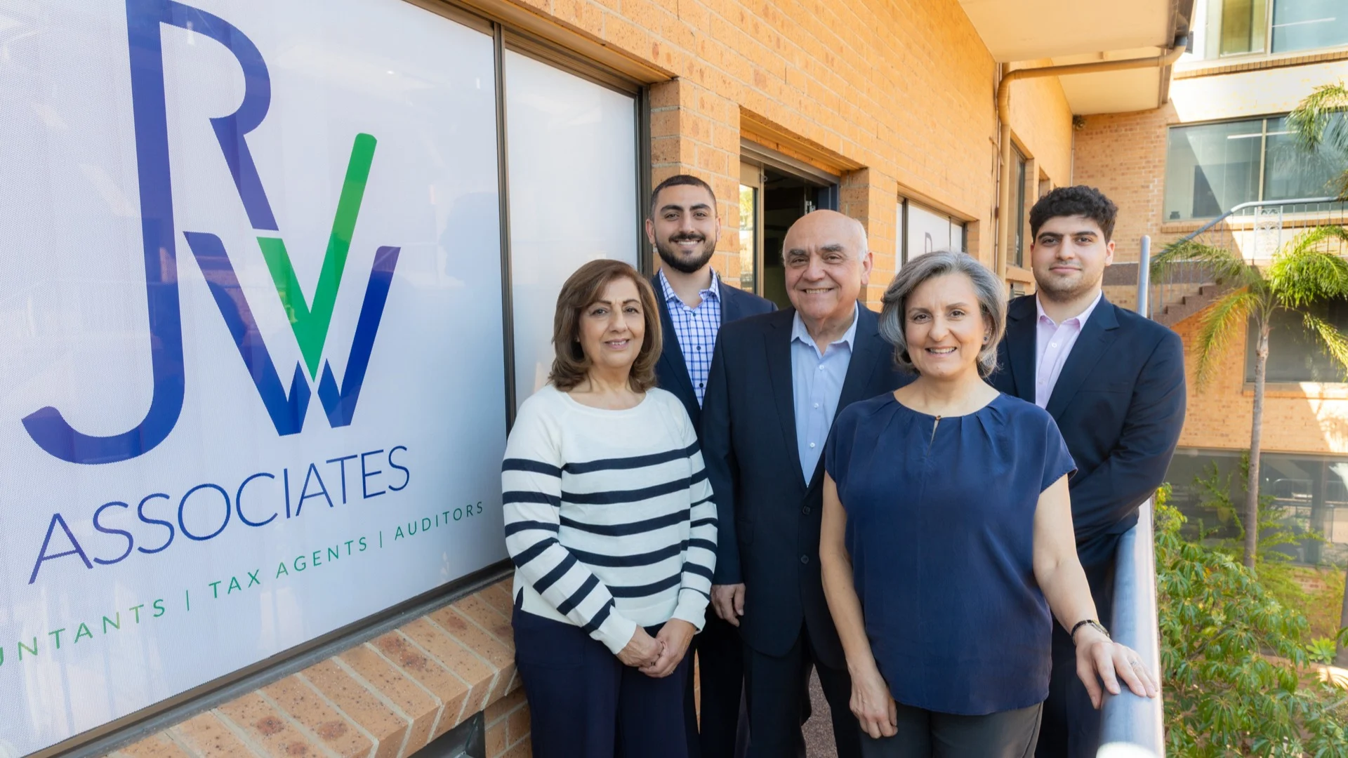 Group of professionals standing outside RJW Associates office with company logo visible on window.