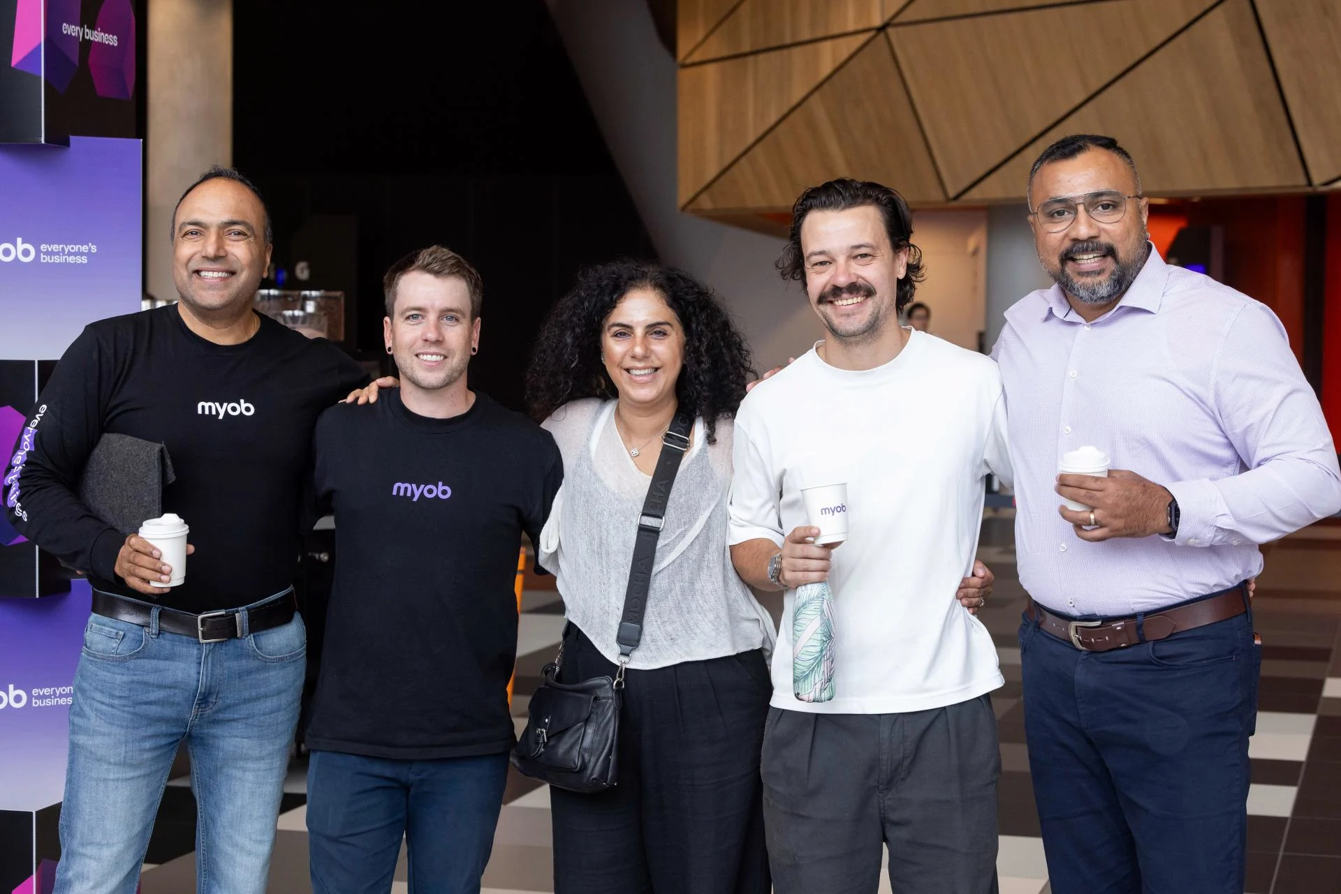 A group of five MYOB team members posing or a photo and smiling while attending the 2026 MYOB All Hands events.