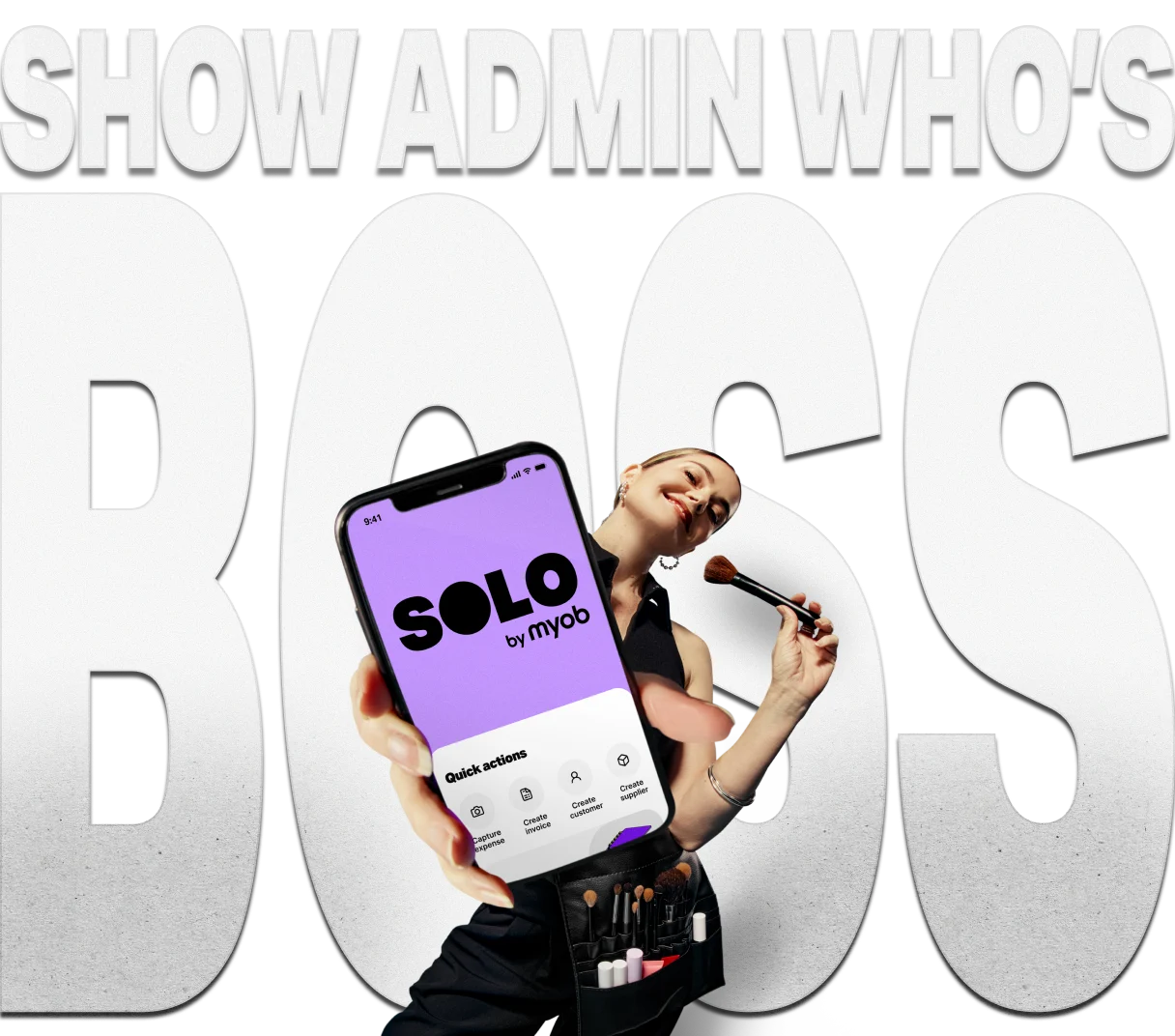 Female sole trader holding her phone displaying the Solo app home screen, standing in front of the words “Show admin who’s boss”.