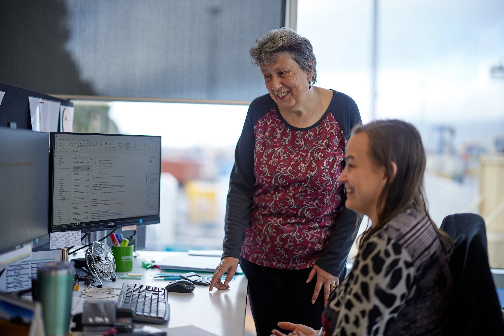 Two Lyttelton Port Company employees at a workstation looking at information on a screen.