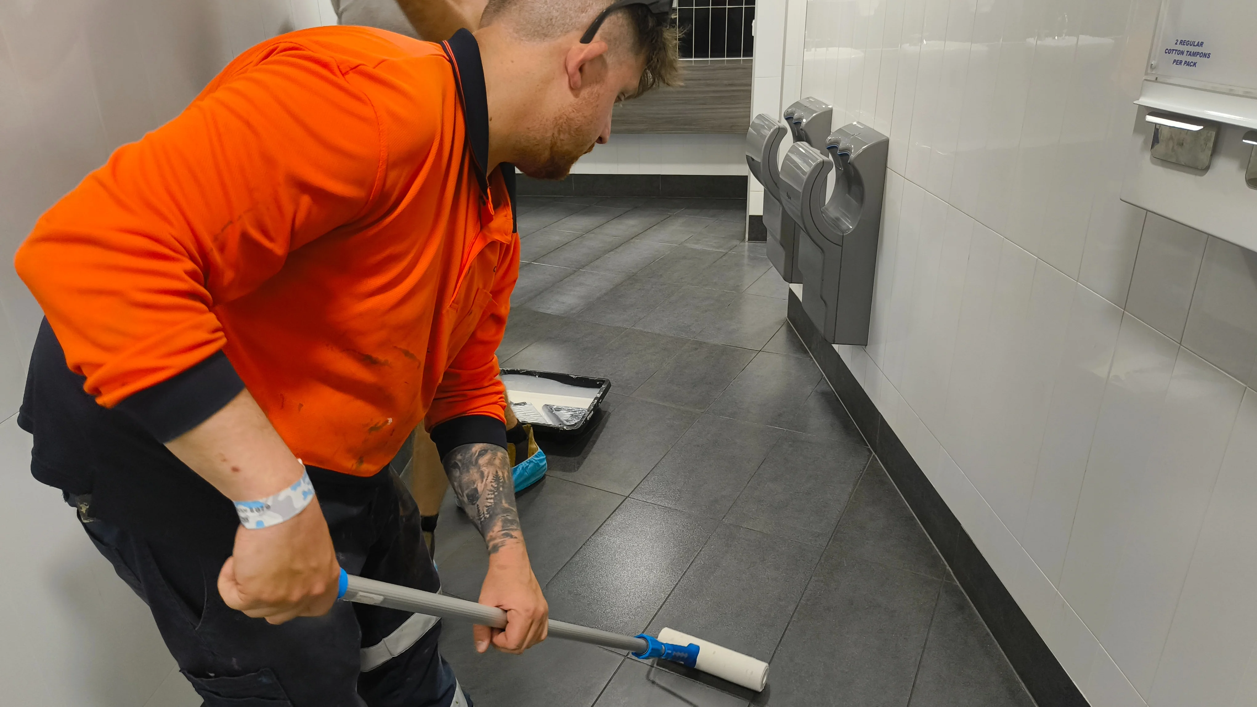 A tradesman tiling a public restroom.