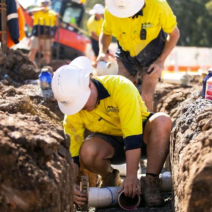 construction-workers-in-trench-laying-pipe
