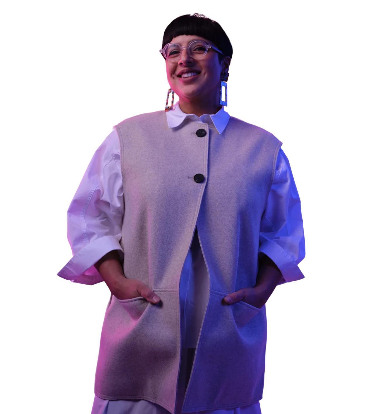 Person with short dark hair wearing glasses, a light gray vest over white shirt, illuminated by pink and blue lighting.