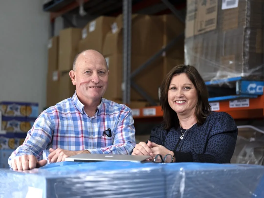 Man-and-woman-sitting-at-desk-in-warehouse 