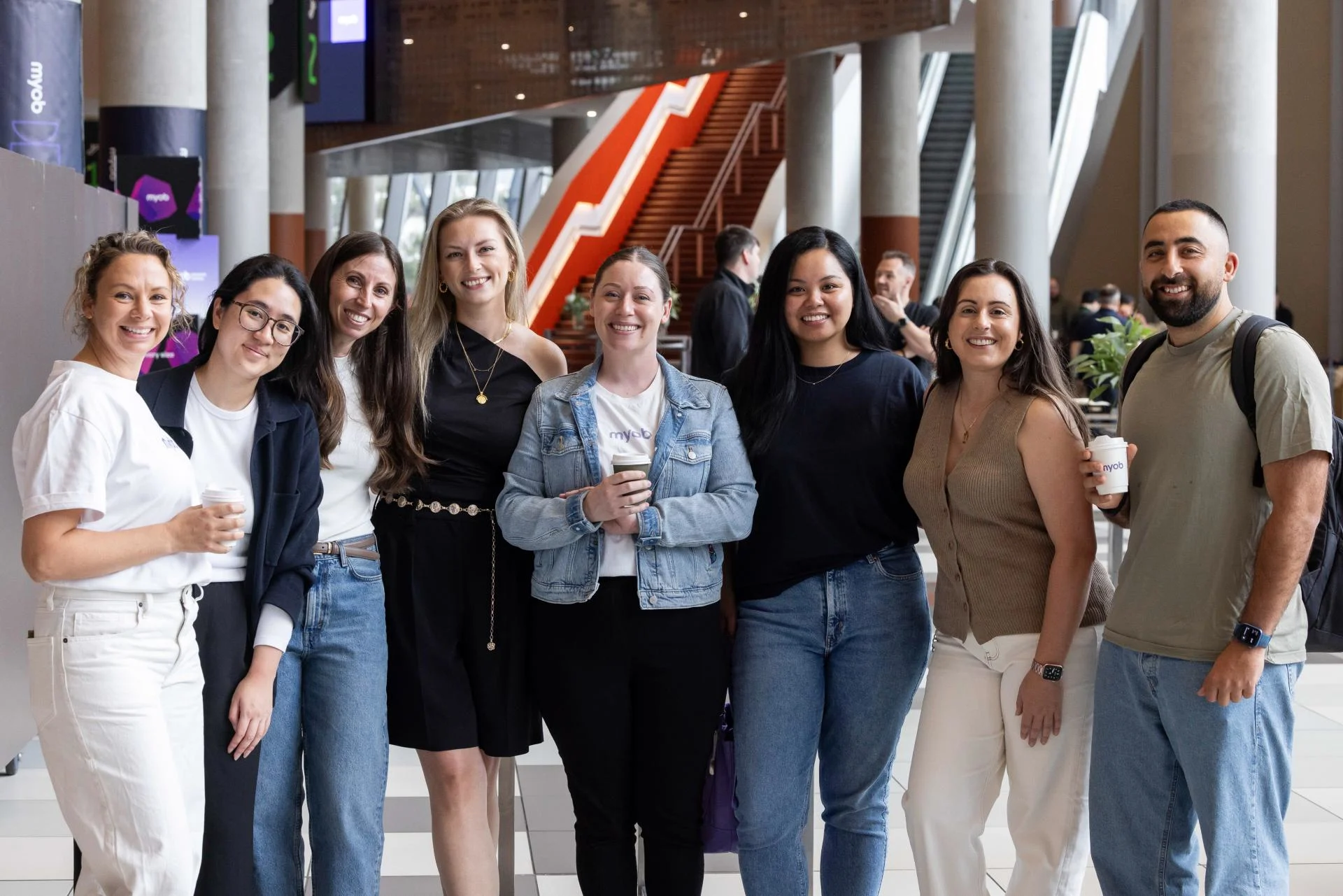 A group of MYOB team members smiling and posing for a photo, while attending the company's annual All Hands event.