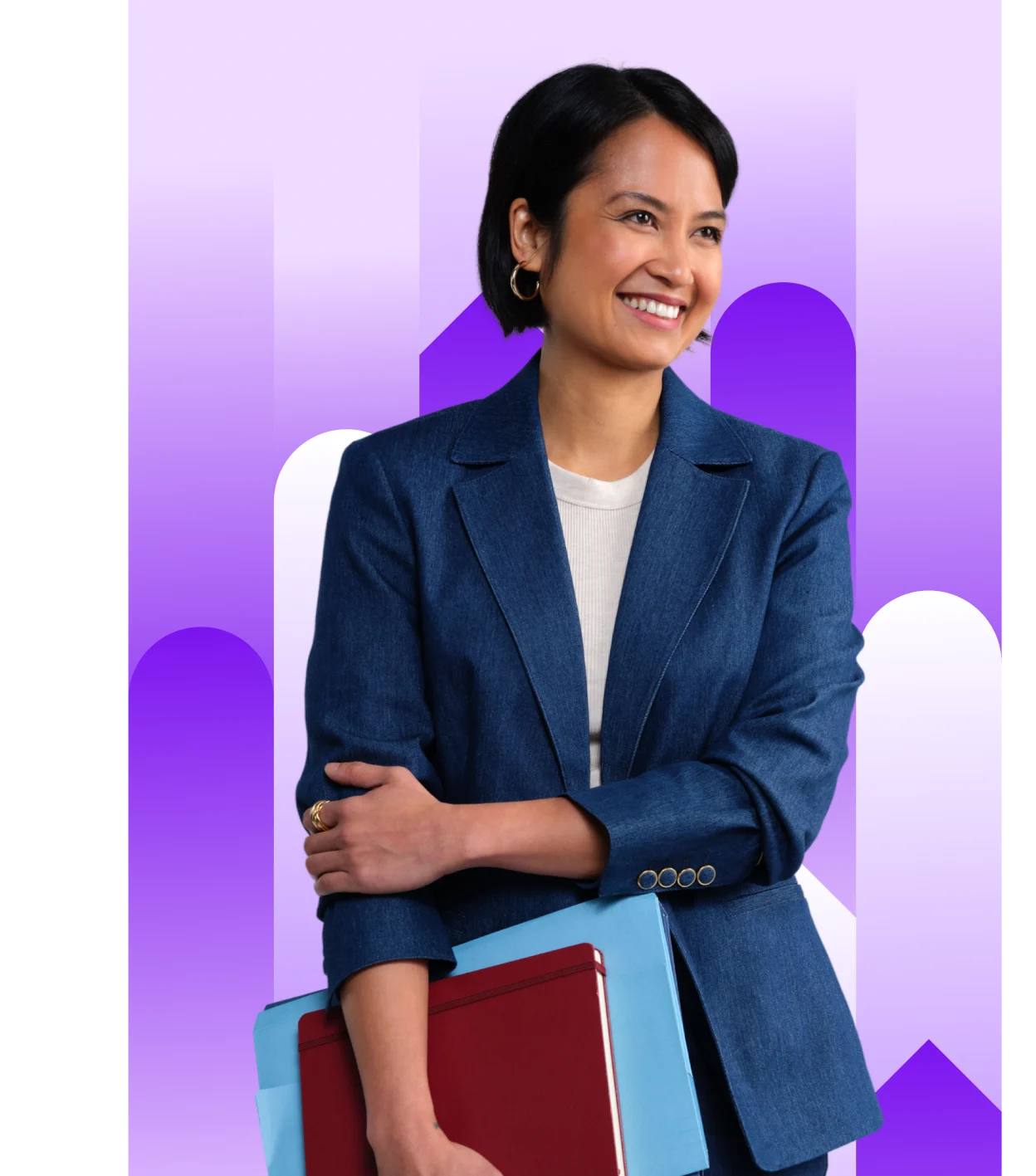 Smiling professional bookkeeper with short dark hair in a navy blue suit jacket and white top, holding red and blue folders, looking off to the side.