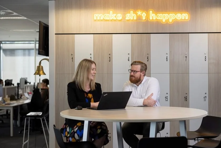 Professional-man-and-woman-sat-at-table-looking-at-laptop