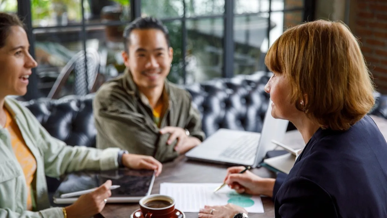 Three professionals discussing business in a coffee shop.