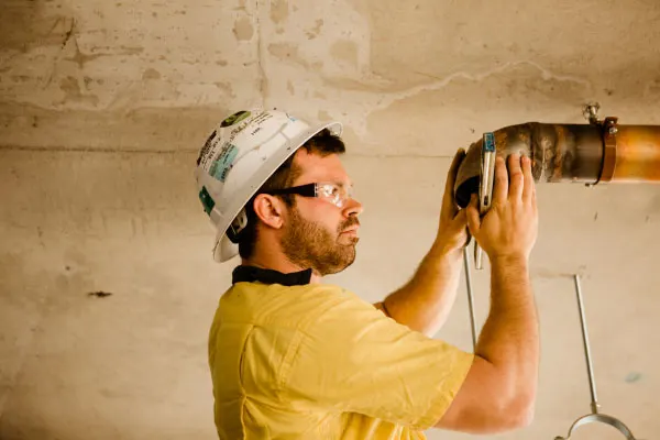 man-in-hard-hat-affixing-piping