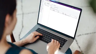 Person typing on a laptop displaying an email interface, viewed from over their shoulder.
