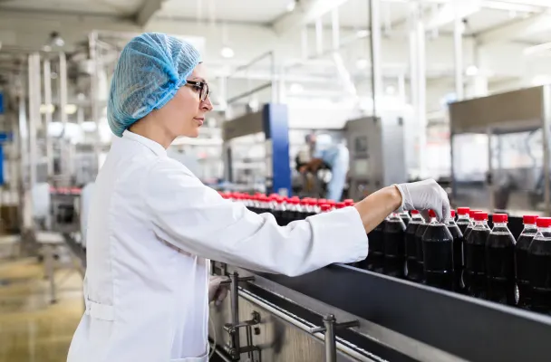 Manufacturing worker in scrubs adjusts stock in a production line. 