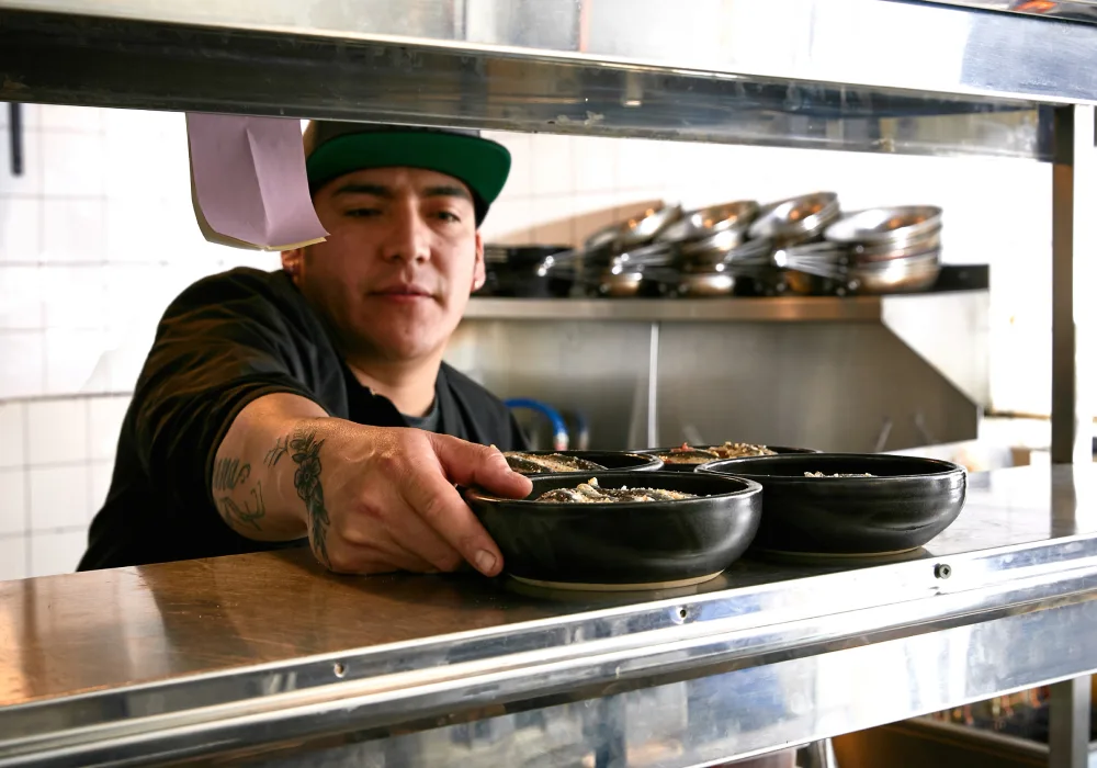 Chef at restaurant places order on counter, ready to bring to customer's table.