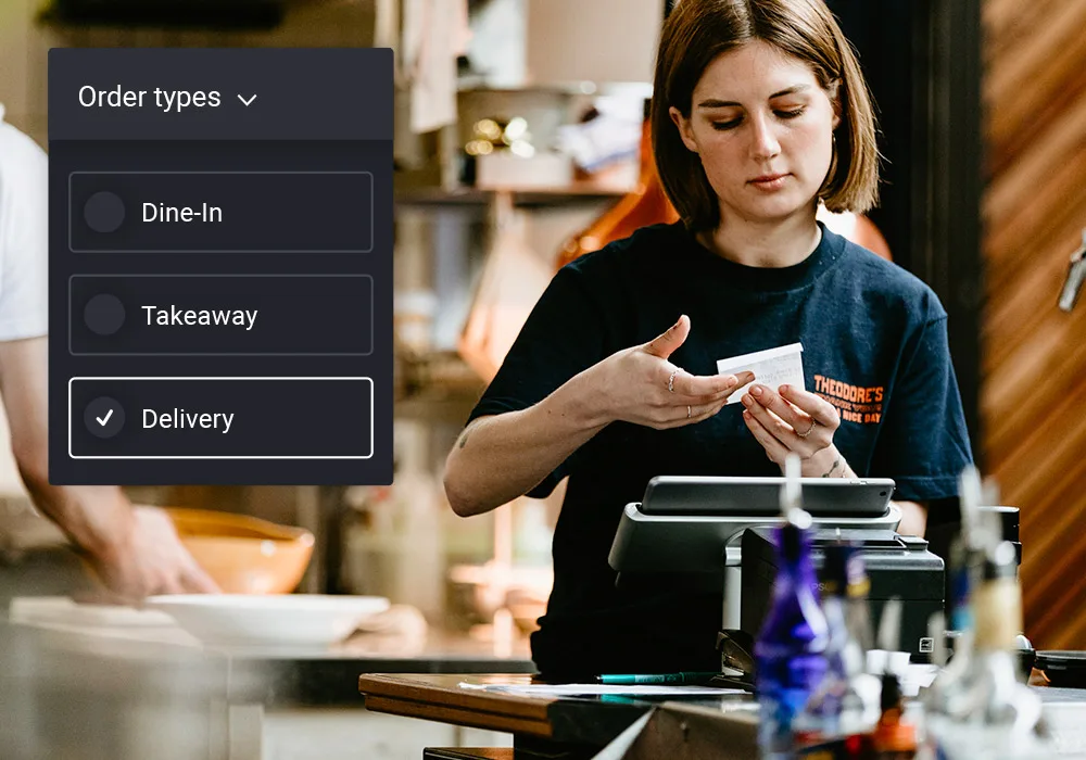 Waiter at restaurant counter looks at receipt. Beside her, a screen capture of the Lightspeed app shows options for dine-in, takeaway or delivery.