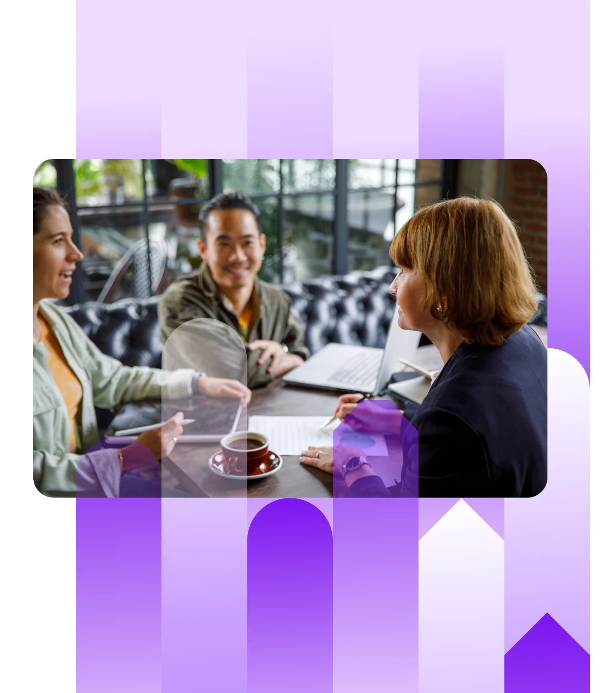 Three professionals having a casual meeting in a cafe or office lounge, reviewing documents and a laptop over coffee. One woman is signing a document.