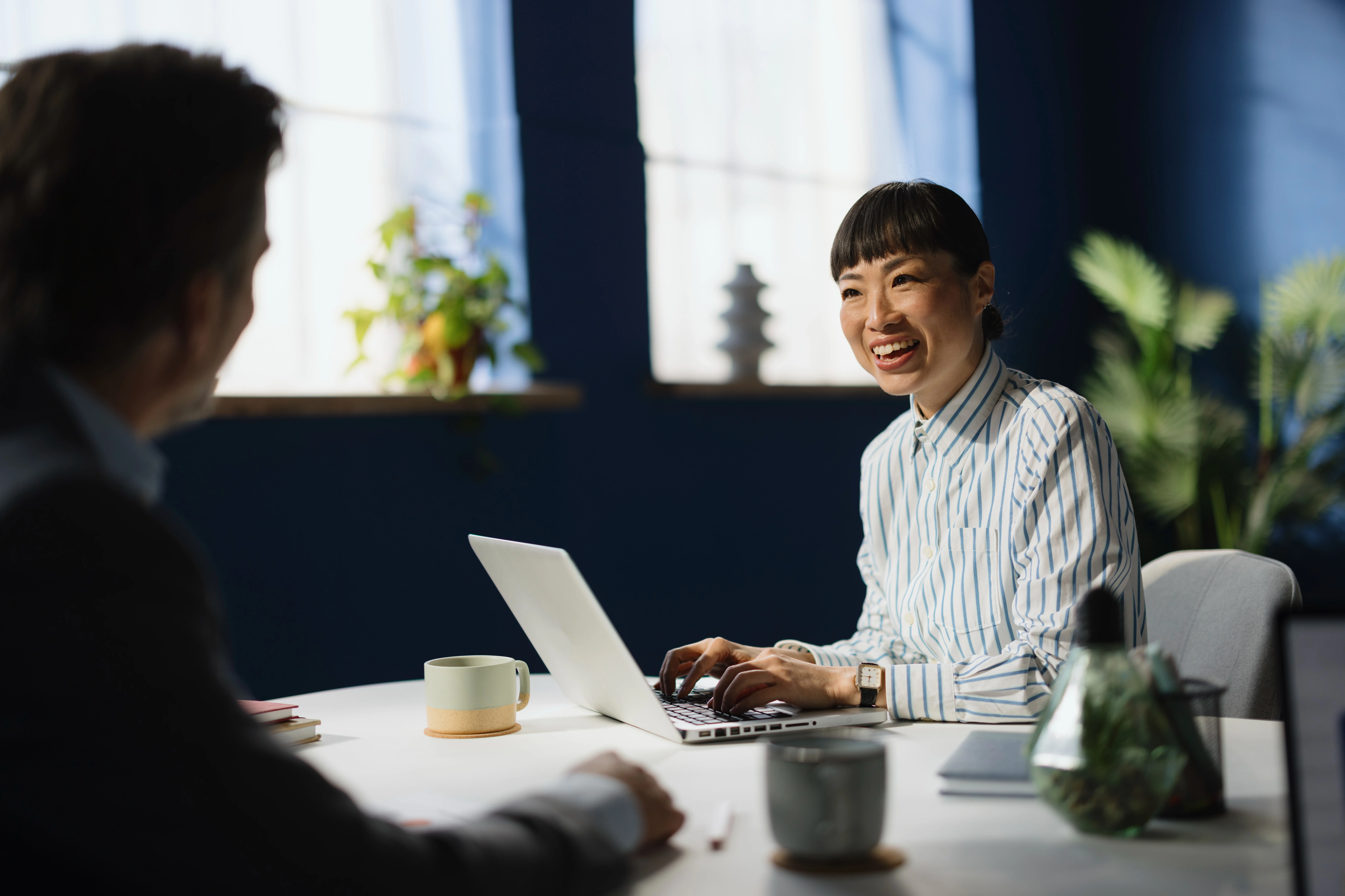 Business woman meeting with colleague in an office, using a laptop.