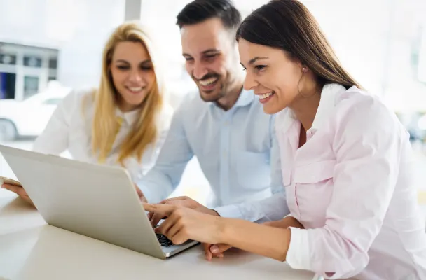 3 smiling people working at a computer