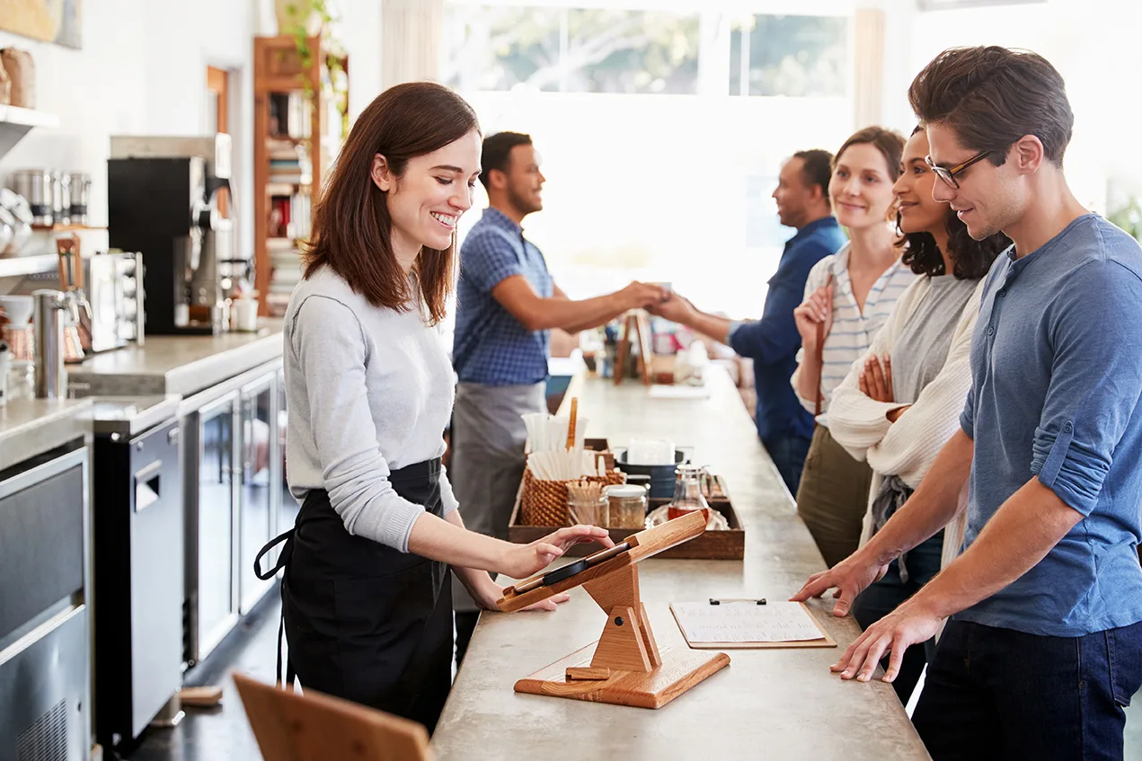 Customers in a cafe setting, lined up to place their order.