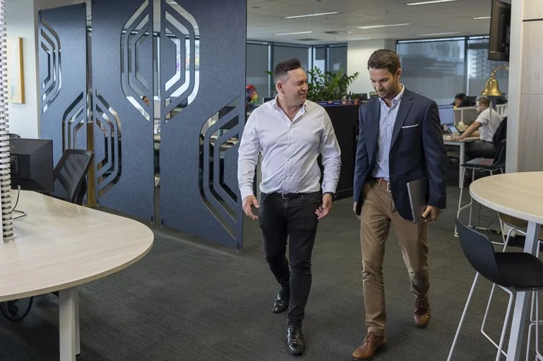 Two-men-walking-and-talking-in-office-environment