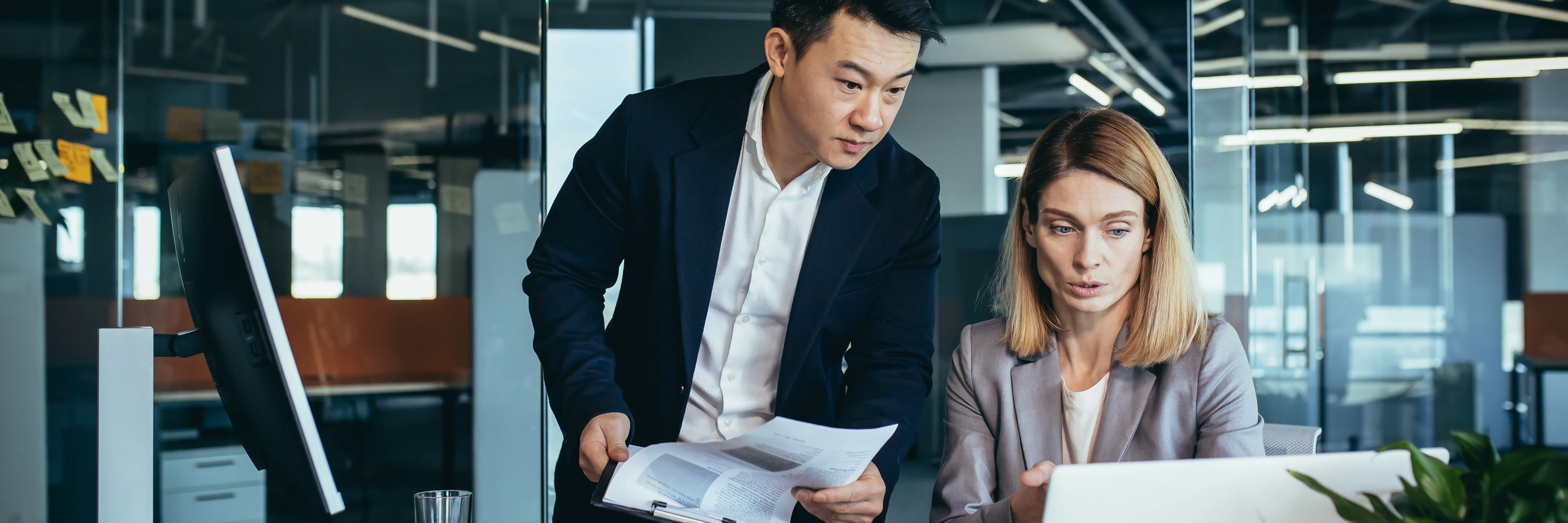 Two professionals in an office analysing performance using ERP software