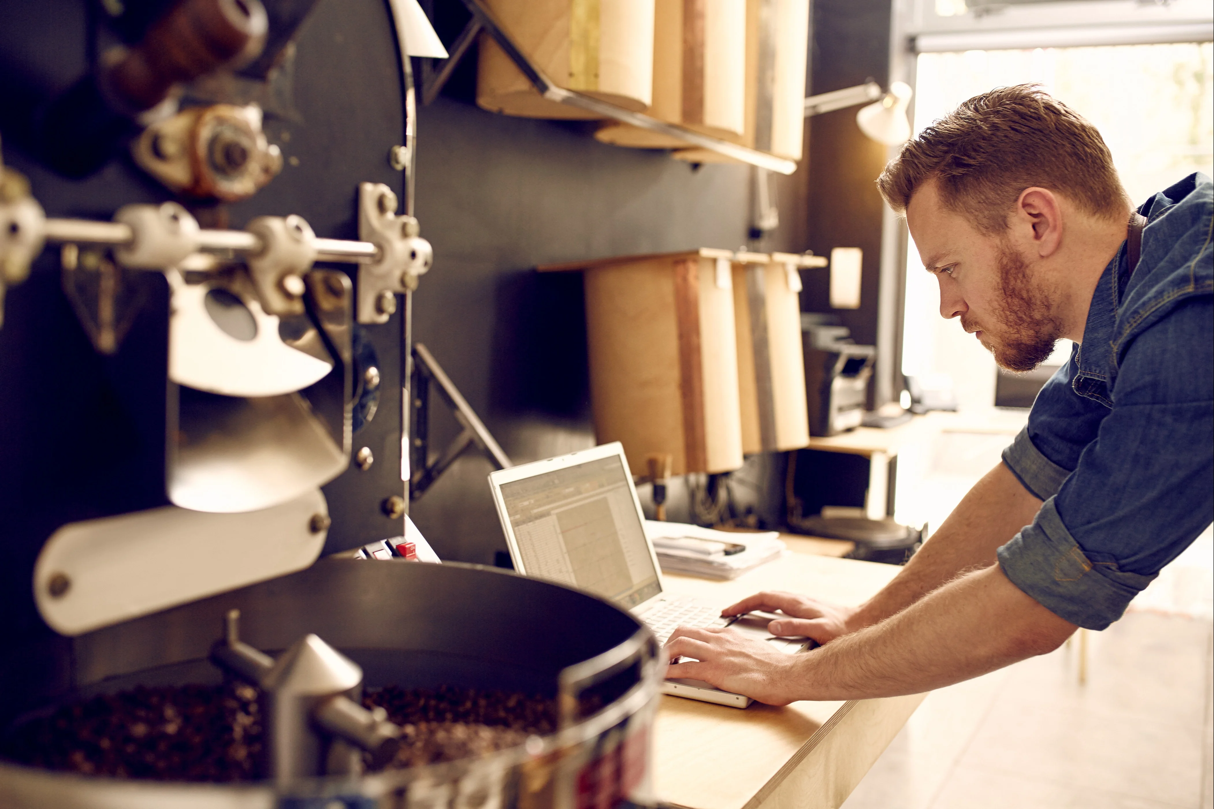 A business owner working on his laptop, whilst in his workshop.