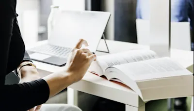 Lady reading book at computer