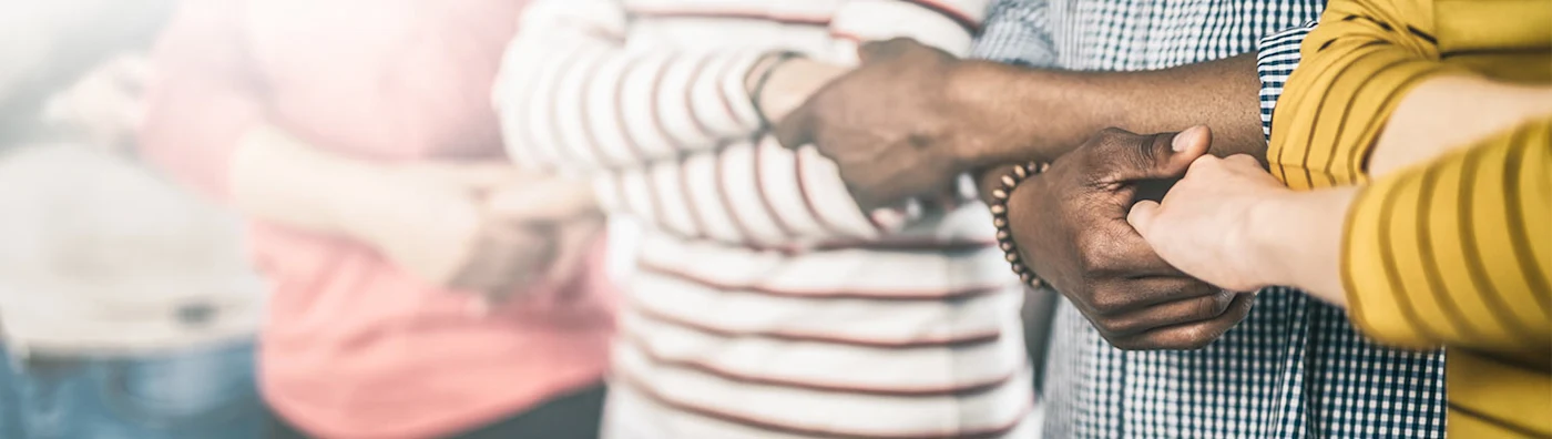 Close up image of 5 people holding hands.