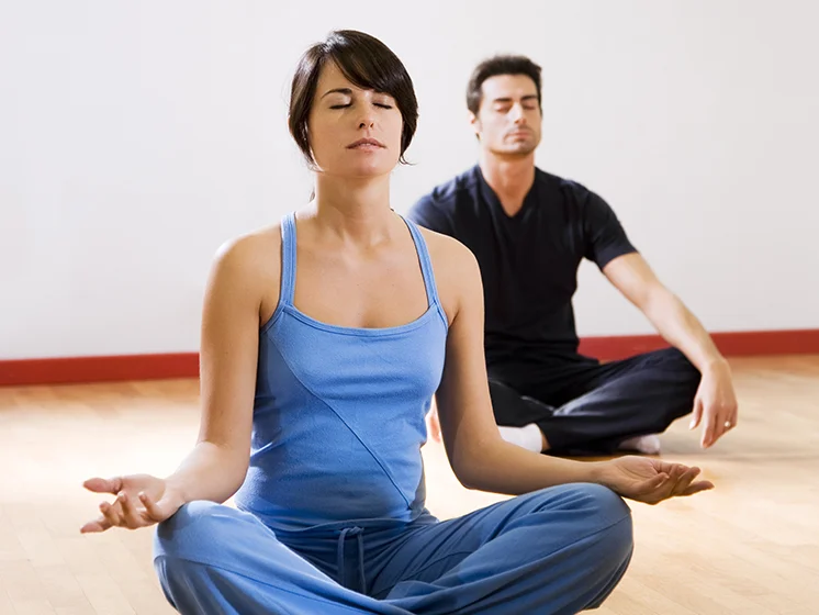 Close up image on a woman and a man meditating with their eyes closed.