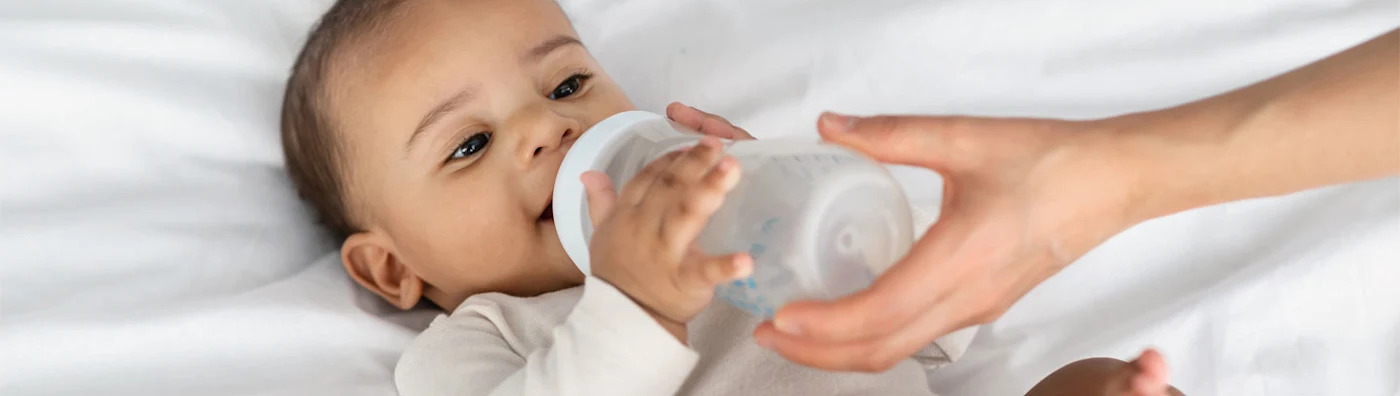 Infant drinking from a baby bottle.