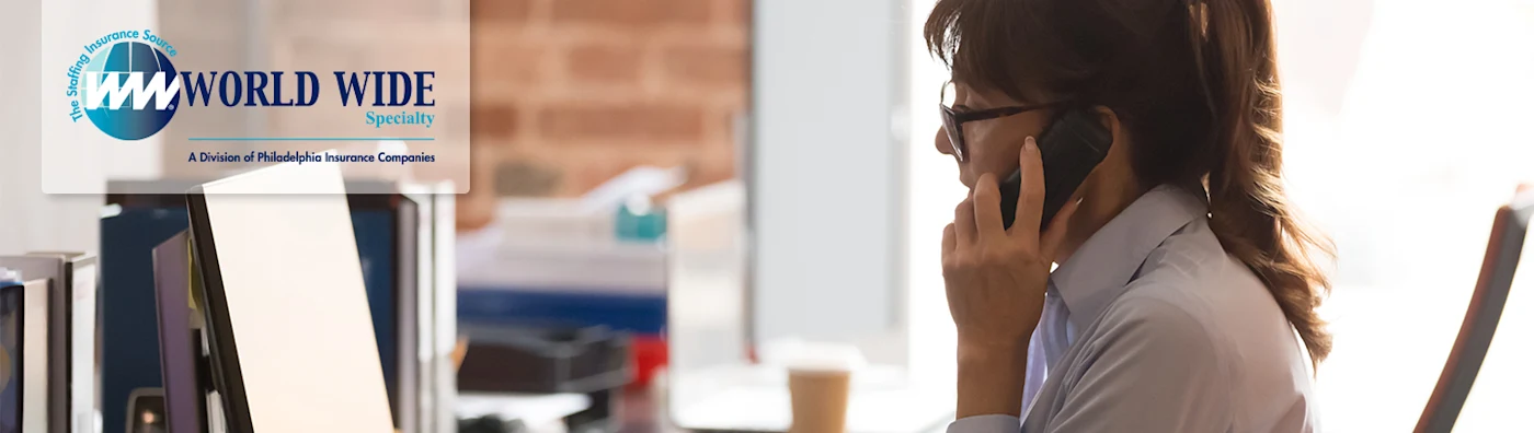 A female temporary office worker multitasking between a phone call and her computer. World Wide Specialty text and logo accompanies image