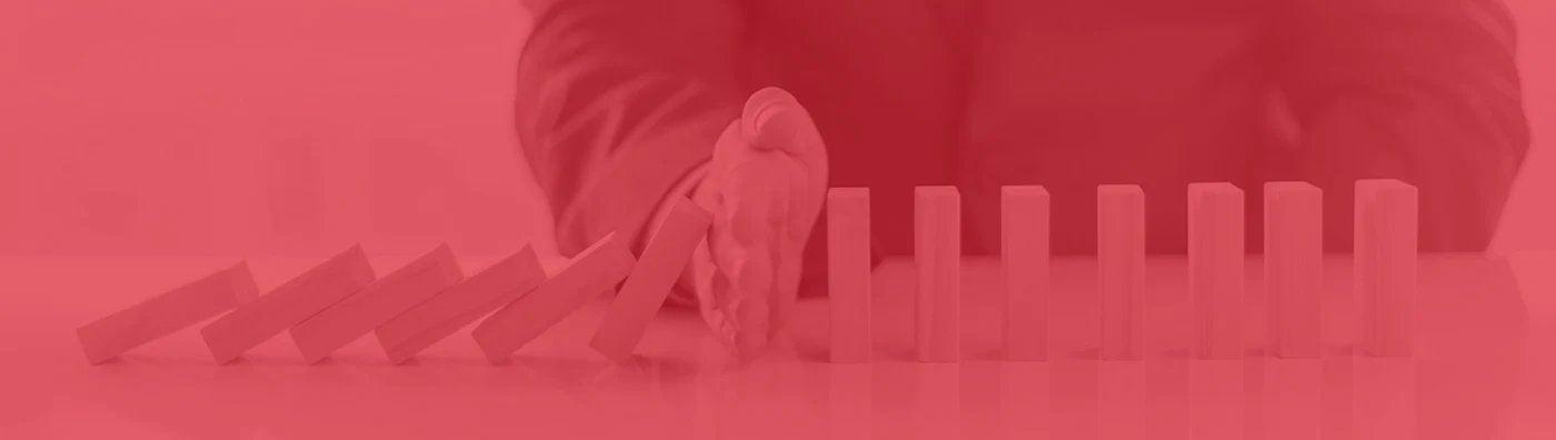 Red filter over a person's hand stopping a chain reaction of blocks falling